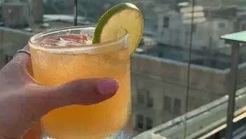 hand holding tropical drink on rooftop